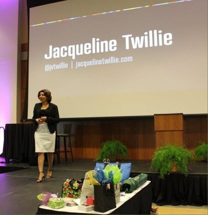 Jacqueline on stage beneath a screen showing her name.