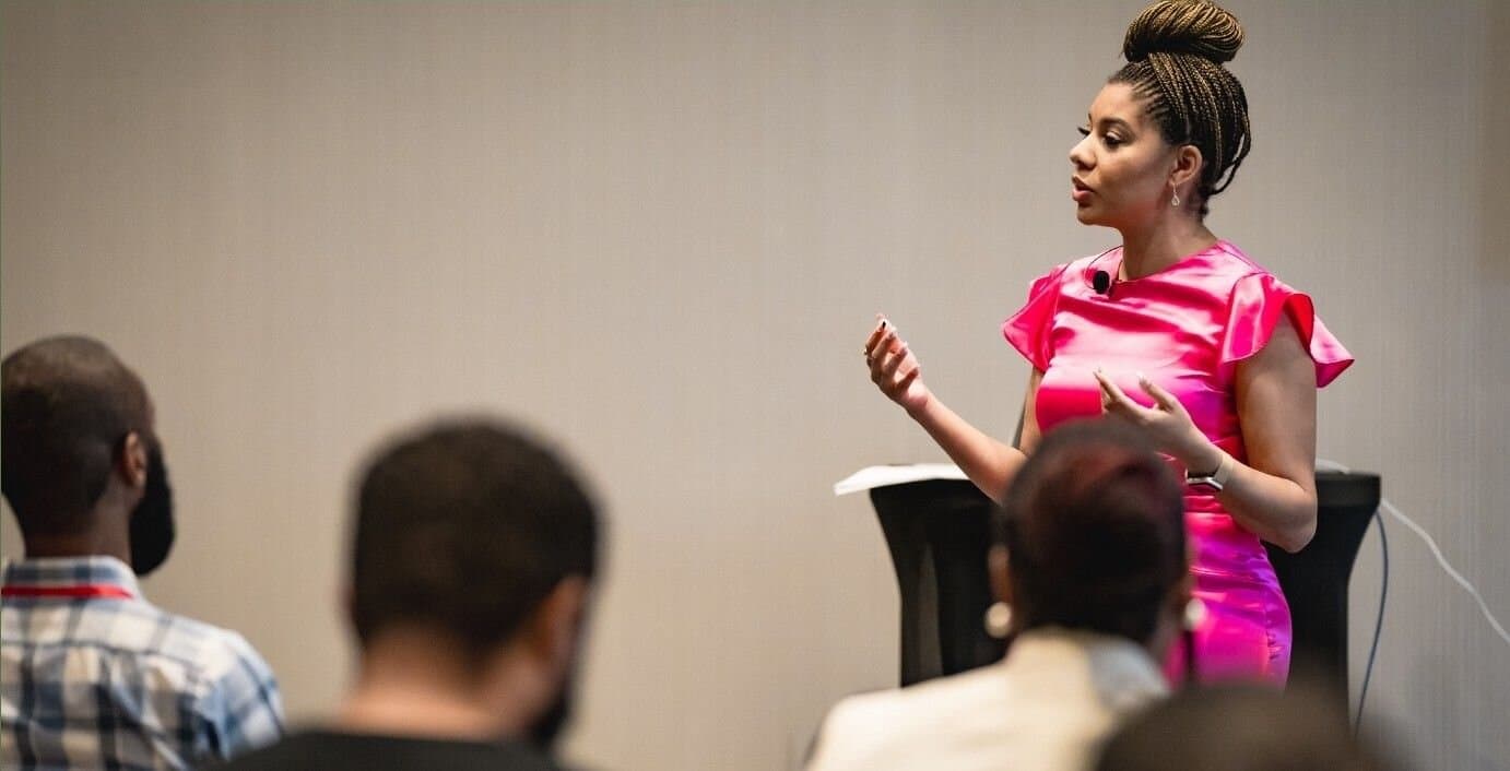 Jacqueline V. Twillie in a pink top, teaching a seated audience.